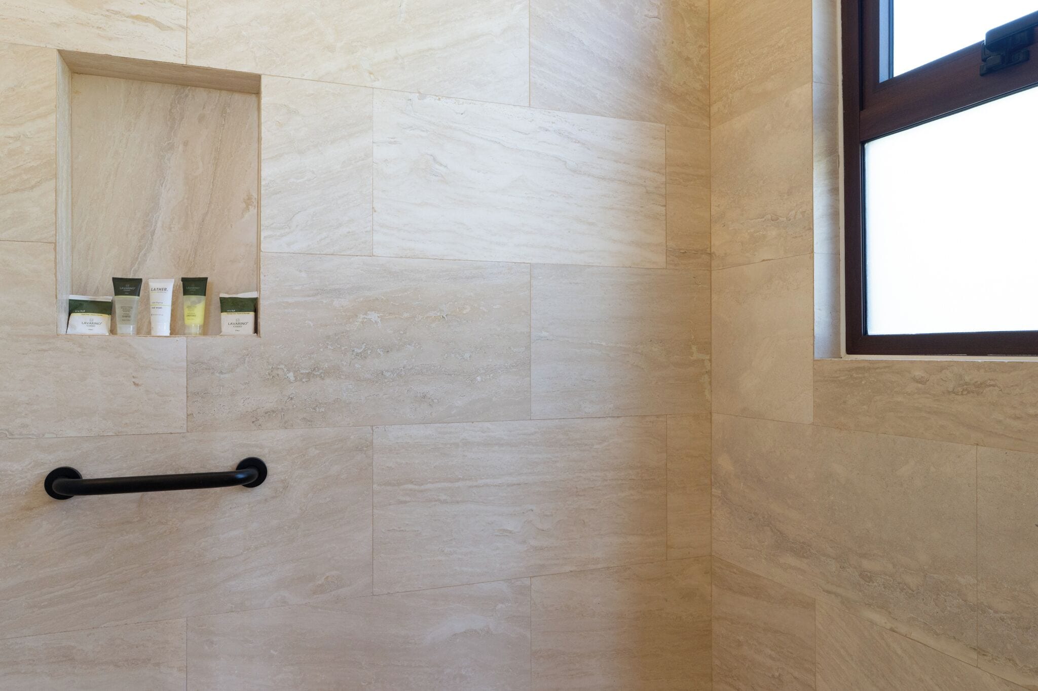 Un bagno con parete in marmo, una finestra e un corrimano.