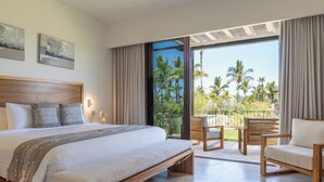 Una habitación de hotel con una cama grande, un balcón con sillas y vistas a palmeras.
