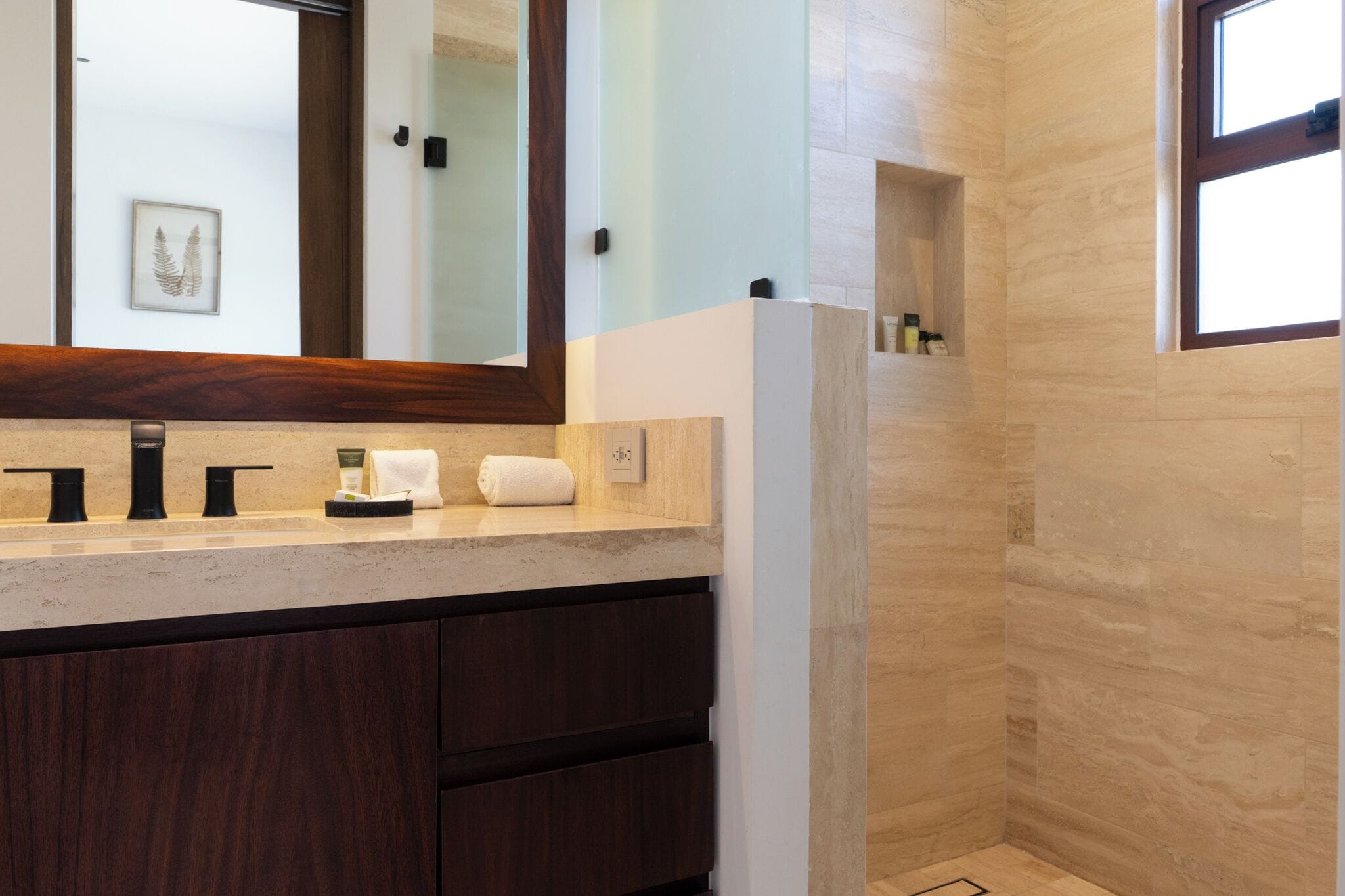 A bathroom with a marble countertop, a mirror, a towel, and a shower area.