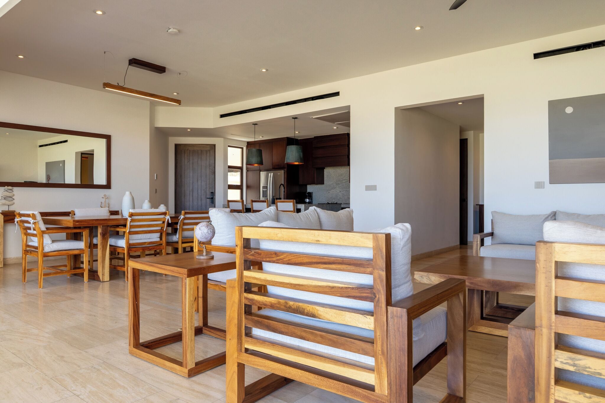 Un salon moderne avec des meubles en bois, un coin repas et une cuisine visible à travers une porte ouverte.
