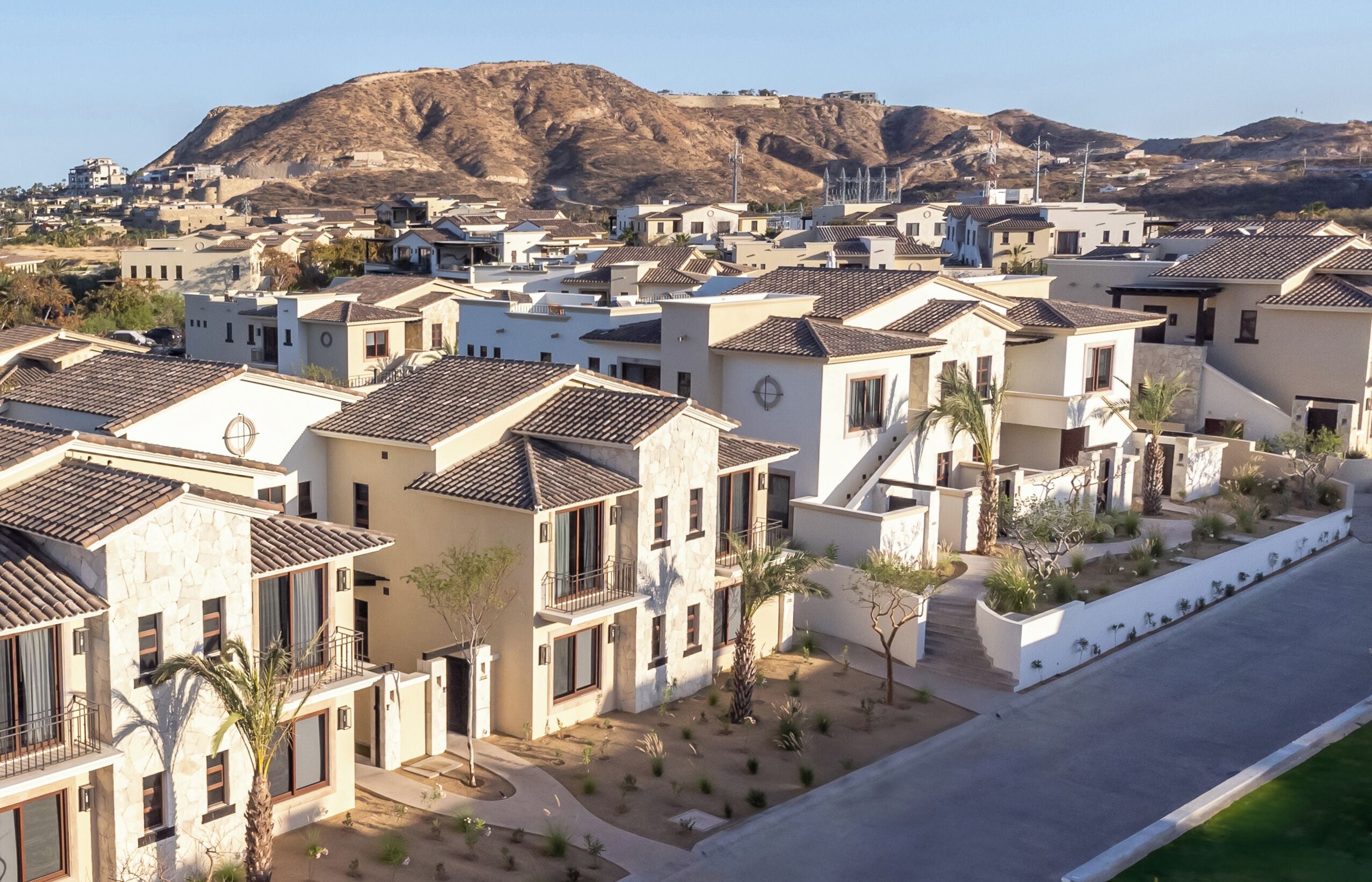 Una zona residencial con casas modernas, una calle y una montaña al fondo.