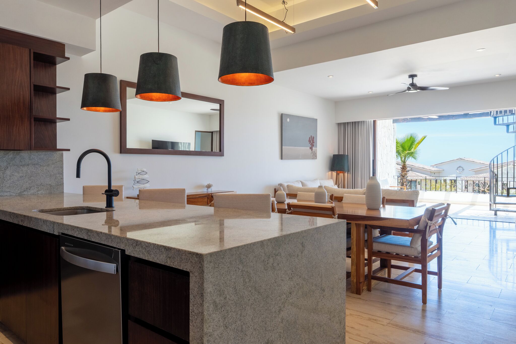 A modern kitchen with a granite countertop, a built-in dishwasher, and pendant lighting.