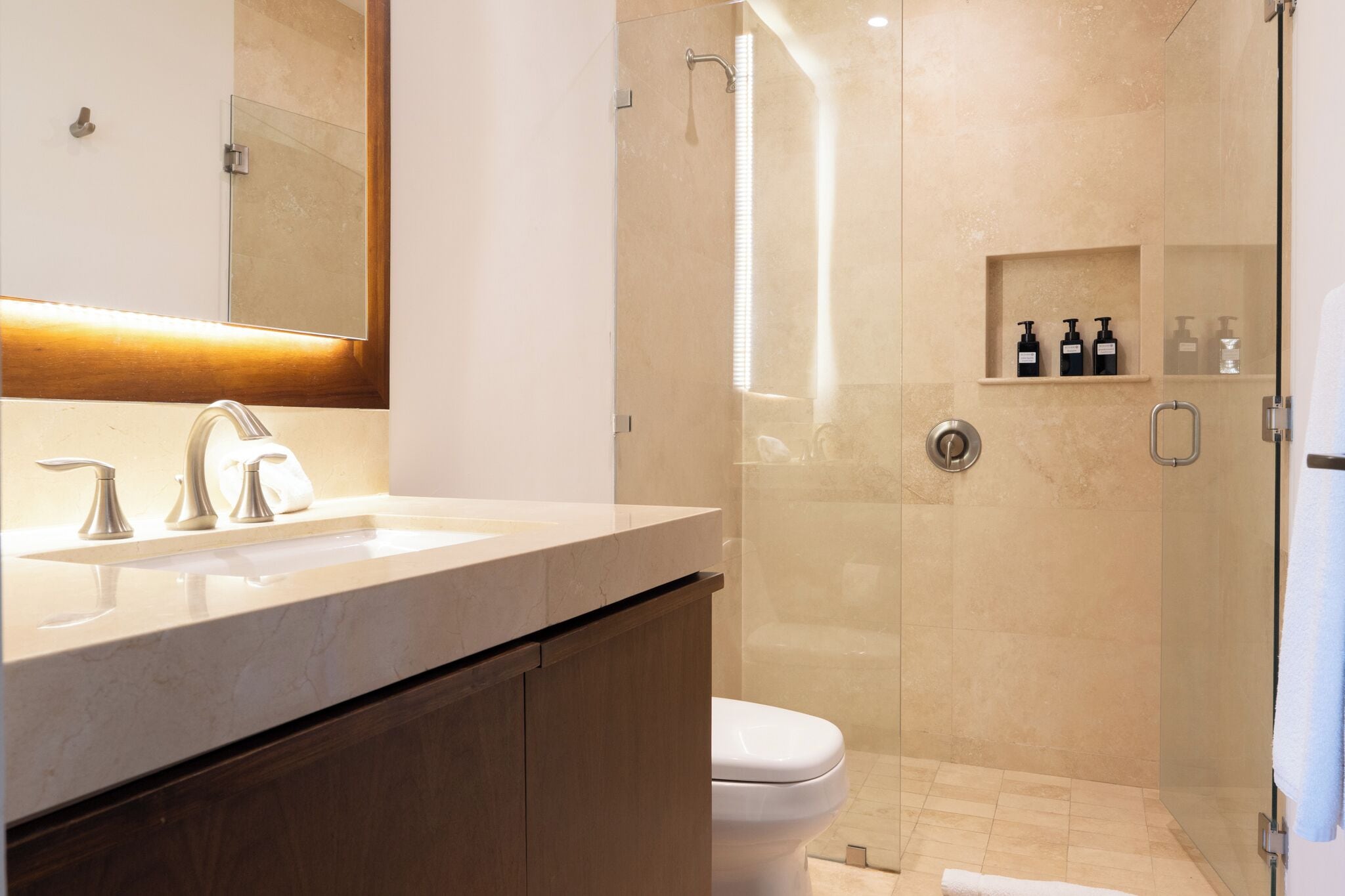 A modern bathroom with a glass-enclosed shower, a vanity with a mirror, and a toilet.