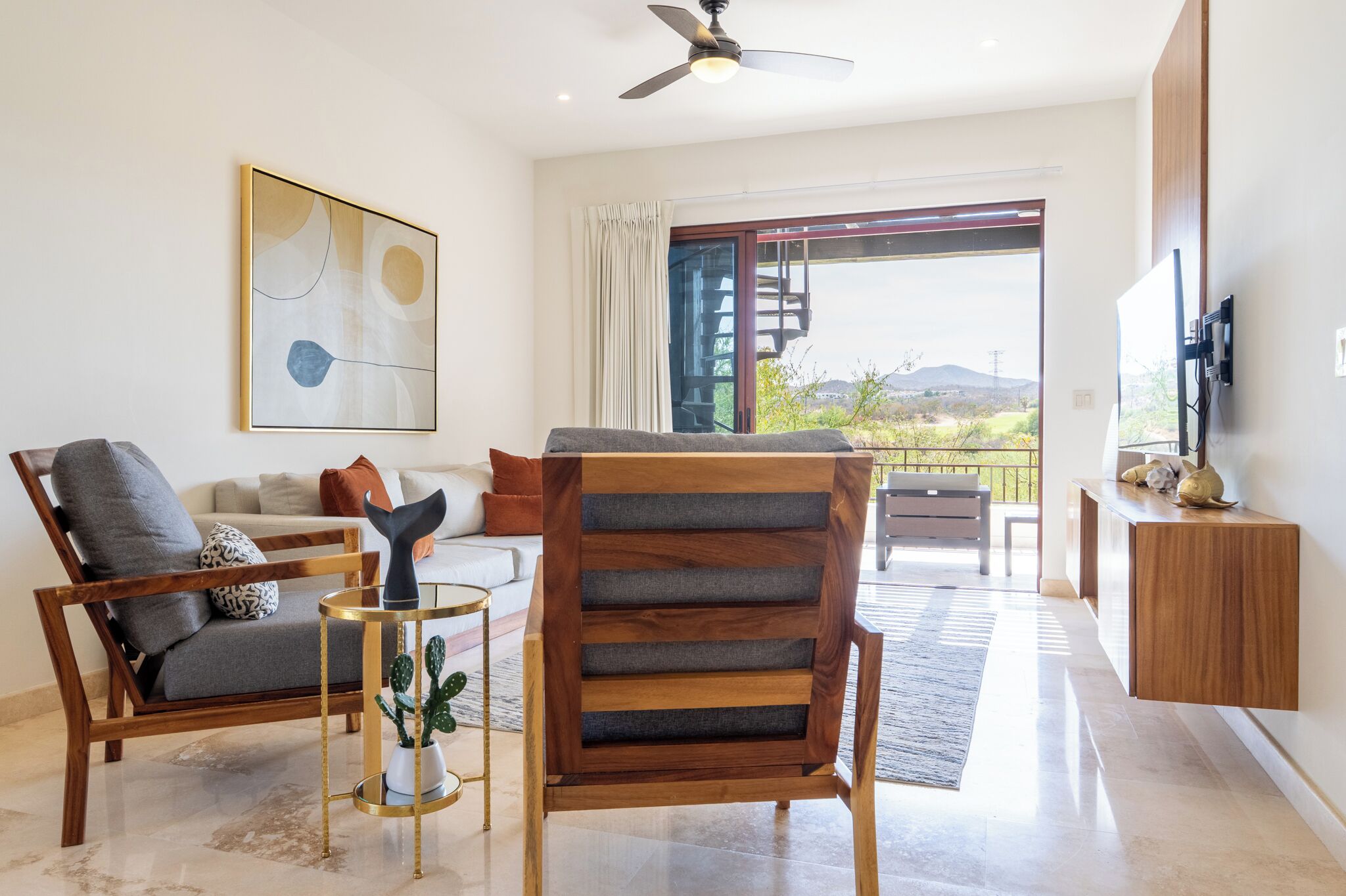 A modern living room with a sofa, a wooden chair, a coffee table, and a ceiling fan.