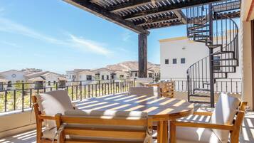 A balcony with wooden furniture, a pergola, and a spiral staircase.