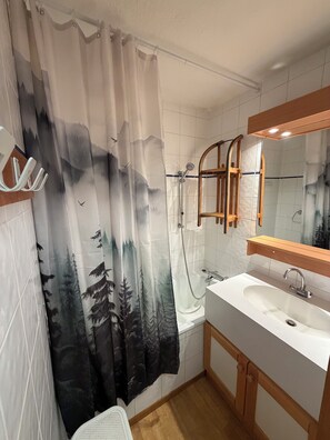 Un baño con ducha, lavamanos y espejo.