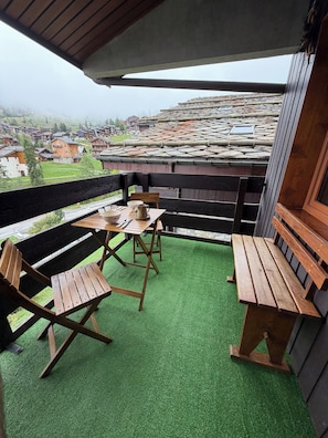 A balcony with wooden furniture, a table, and chairs.