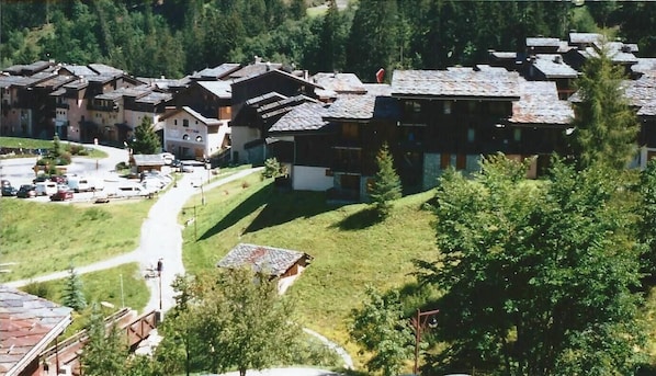 A cluster of traditional chalet-style buildings with sloped roofs, surrounded by greenery and a winding road.
