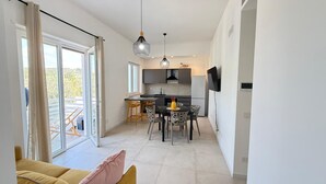 A modern kitchen with a dining area, large windows, and a flat-screen TV. - 'Pilone Del Monaco 9' Apartment with Pool, Sun Deck, and Outdoor Garden (Macchia di Mauro-Pilone)