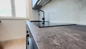 A kitchen with a dark marble countertop, a stainless steel range hood, and a window with a view. - 'Pilone Del Monaco 9' Apartment with Pool, Sun Deck, and Outdoor Garden (Macchia di Mauro-Pilone)