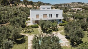 A modern two-story house with a flat roof, surrounded by olive trees and a clear sky. - 'Pilone Del Monaco 9' Apartment with Pool, Sun Deck, and Outdoor Garden (Macchia di Mauro-Pilone)