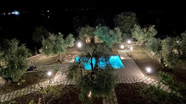 A nighttime view of a swimming pool surrounded by trees and illuminated by street lamps. - 'Pilone Del Monaco 9' Apartment with Pool, Sun Deck, and Outdoor Garden (Macchia di Mauro-Pilone)