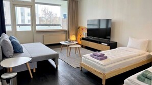Een hotelkamer met een bed, een slaapbank, een televisie, een tafeltje en een raam.