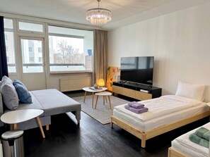 A hotel room with a bed, a sofa, a TV, a small table, and a window. - Modern Nordic Stay in Helsinki Center with Pool, Sauna & Gym (Helsinki)