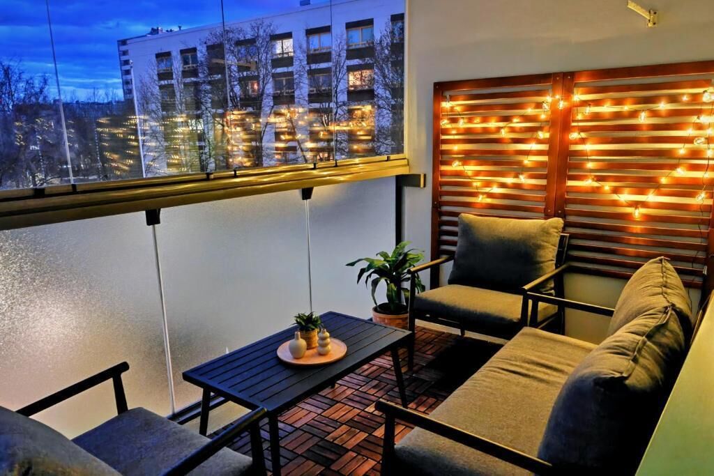 A balcony with a sofa, a table, and a potted plant.