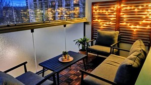 Een balkon met een bank, een tafel en een potplant.