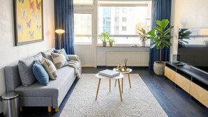 Een moderne woonkamer met een bank, salontafel, televisie en potplanten.