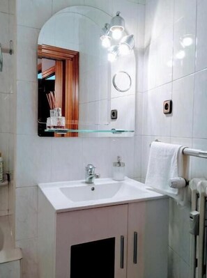 Ein Badezimmer mit weißem Waschbecken, einem Spiegel, einem Handtuchhalter und einer Toilette.