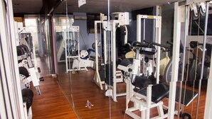Un gimnasio con equipo de ejercicio, suelo de madera y un espejo.