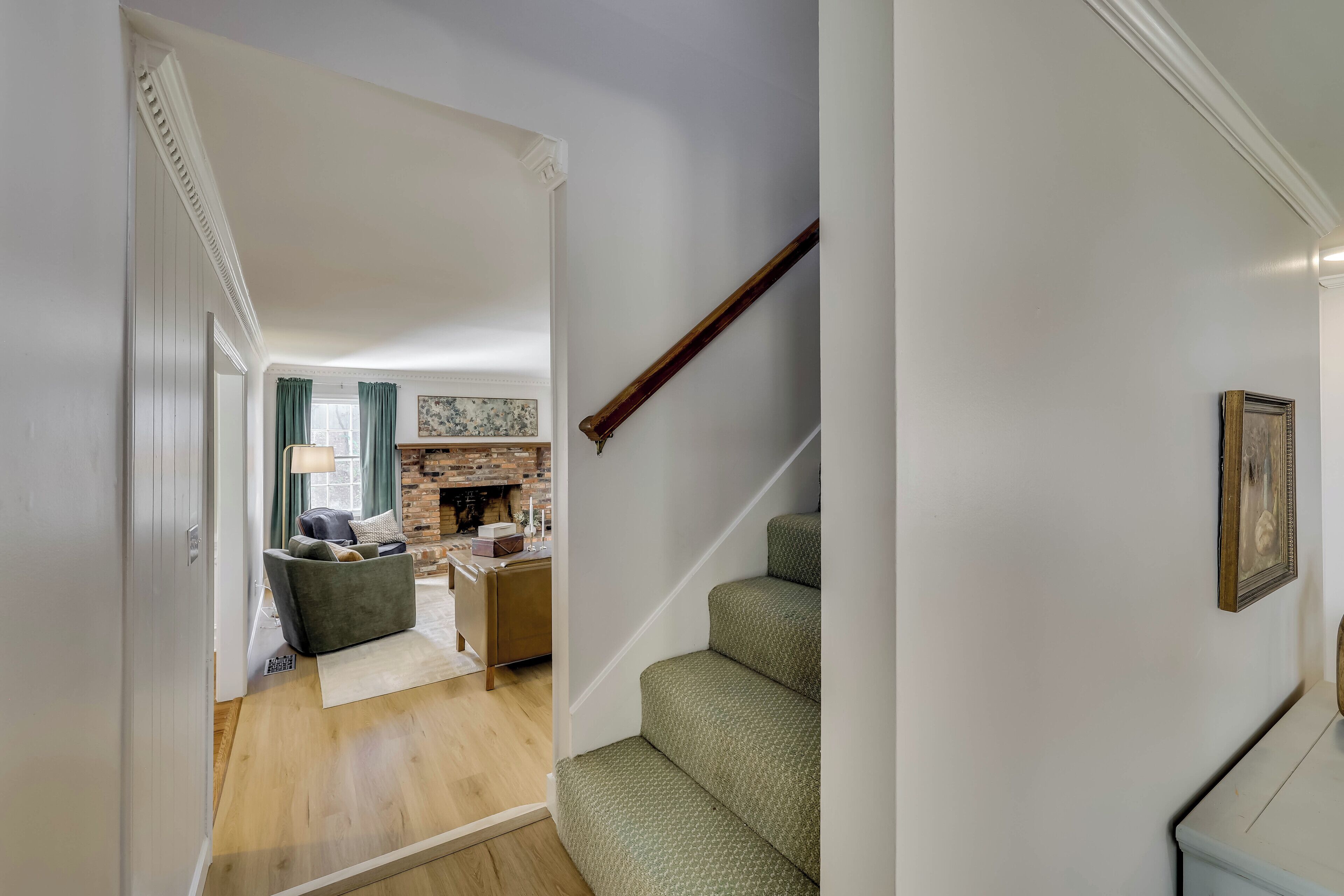 A staircase with a wooden handrail and a green patterned carpet.