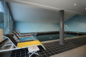 A swimming pool area with lounge chairs, a tiled floor, and a tall pillar. - Cosy Forest Retreat Near Slopes (Les Angles)