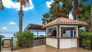A wooden deck with a covered seating area, a kiosk, and a view of the ocean. - San-nicolao Beachfront Stay for 4 (San-Nicolao)