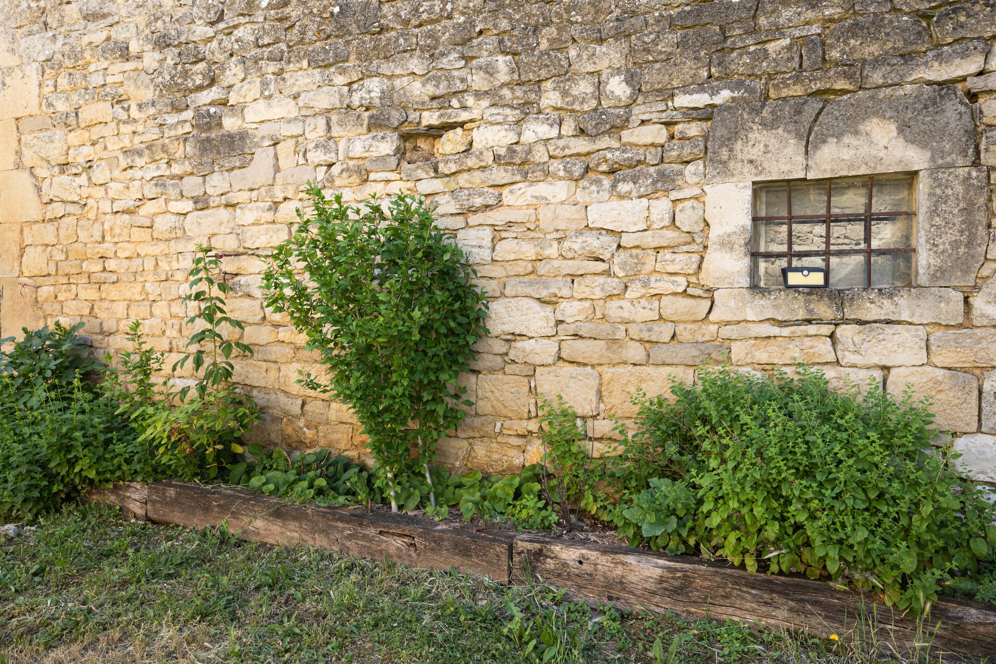 A stone wall with a window and a wooden beam.