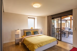 Camera da letto moderna con un letto grande, comodini, una finestra e una porta scorrevole in vetro che dà su una zona esterna.
