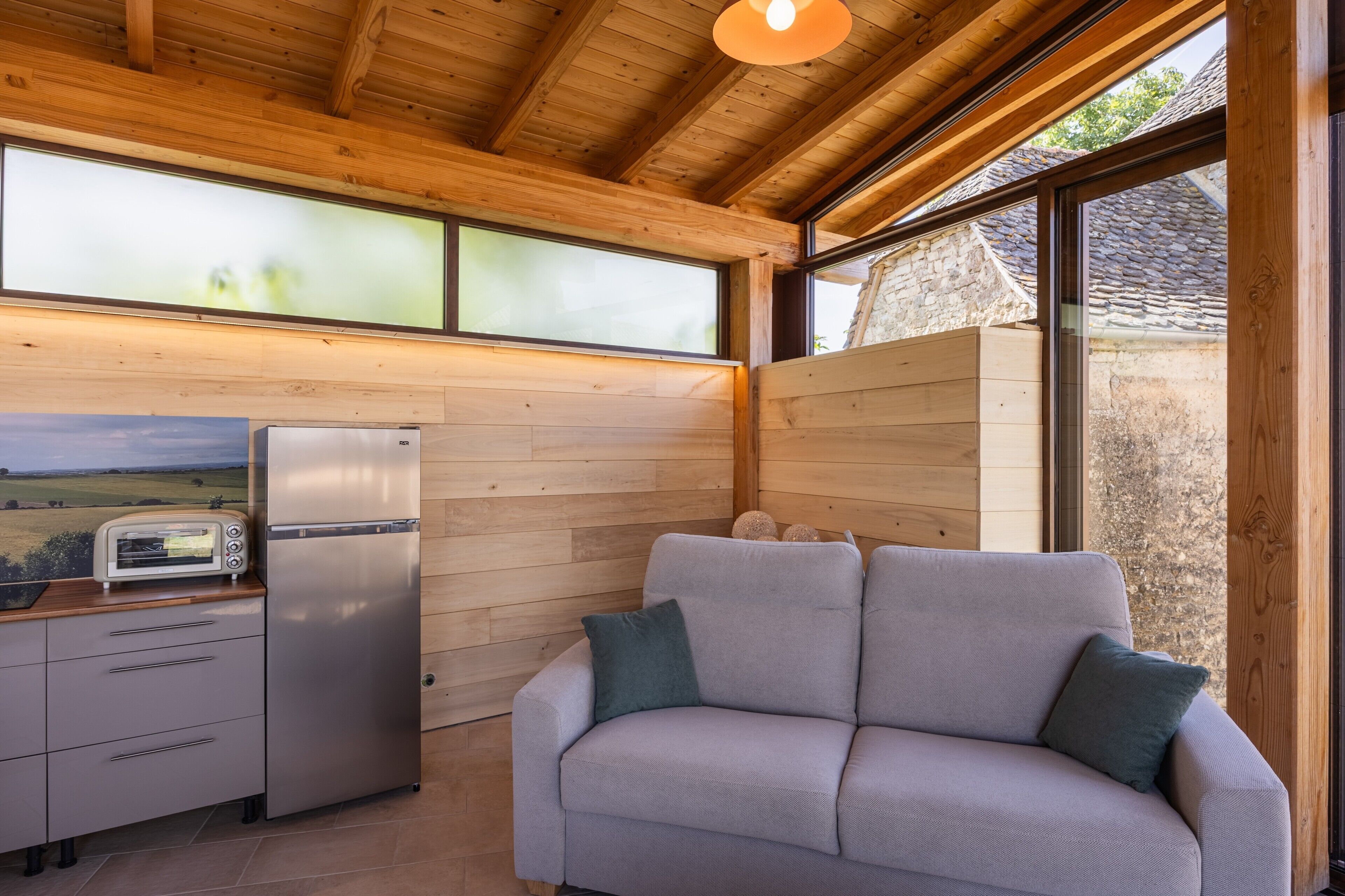 A modern kitchen with a built-in toaster, a refrigerator, and a wooden ceiling.
