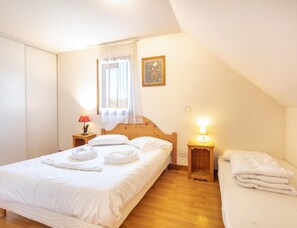 Ein Schlafzimmer mit einem Bett, zwei Nachttischen, einem Fenster mit Vorhängen, einem Wandbild und einem Holzboden.