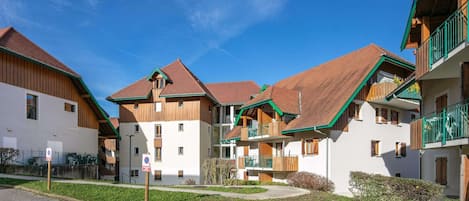 Une rangée de bâtiments de style chalet traditionnel, avec des façades en bois et des toits à deux versants, disposés autour d’une cour.