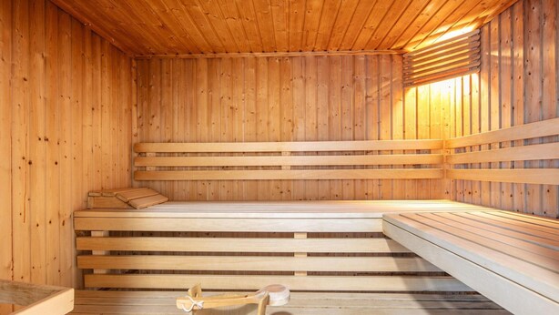 Eine Sauna mit Holzbänken und einem Holzeimer.