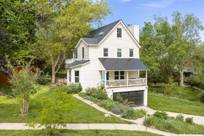 Ein zweistöckiges Haus mit Veranda, Garage und gepflegtem Rasen.