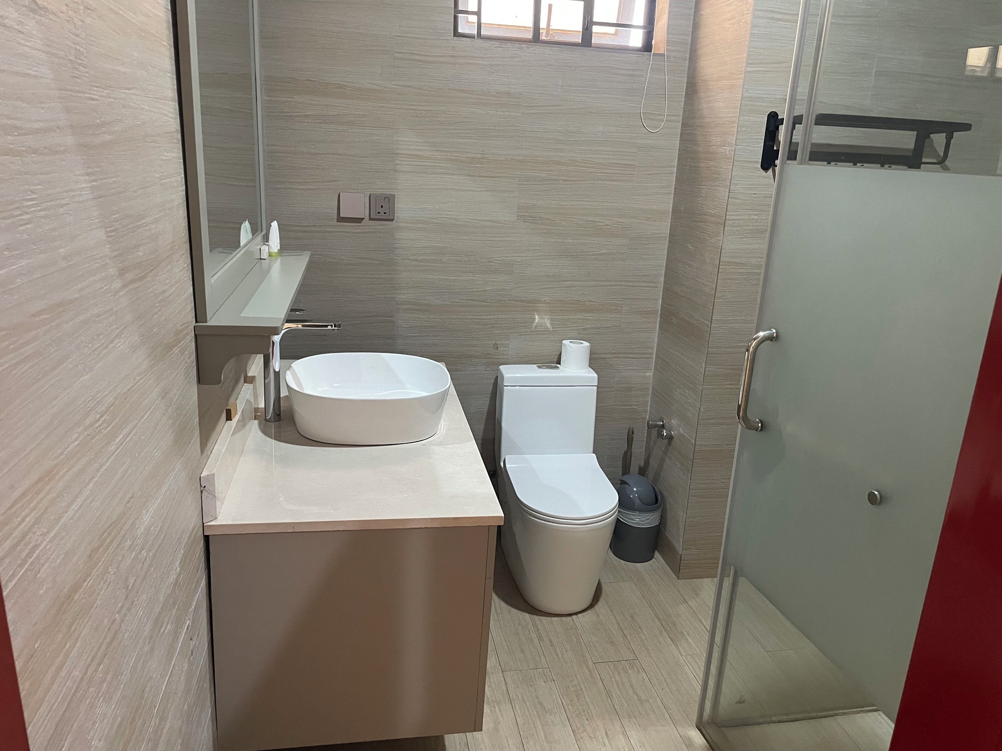 Un baño moderno con un lavamanos redondo, inodoro y cabina de ducha de vidrio.