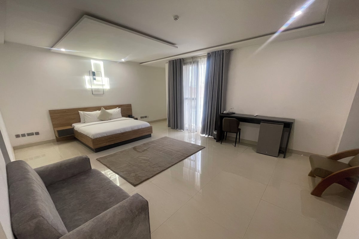 Una habitación de hotel moderna con cama, escritorio, silla y sofá.