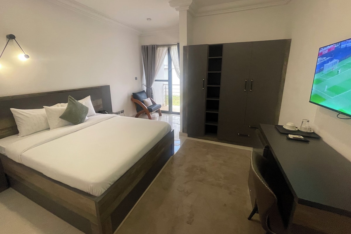 Una habitación de hotel con cama, escritorio, televisor y armario.