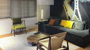 Een modern interieur met een bank, stoelen, een bijzettafeltje en een muurschildering.