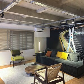 Ein modernes Interieur mit einer Couch, Sesseln, einem Couchtisch und Wandbild.