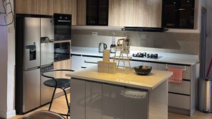 Een moderne keuken met een centraal eiland, roestvrijstalen apparatuur en hanglampen.