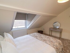 A bedroom with a bed, a window, a radiator, a dresser, and a mirror. - Trafalgar II (Scarborough)