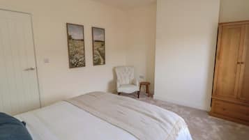 Une chambre à coucher comprenant un lit, une chaise, une armoire et deux tableaux accrochés au mur.