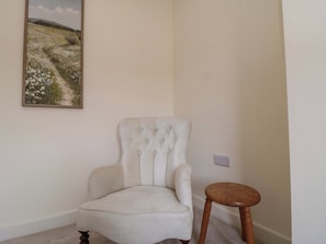 A corner room with a white armchair and a small wooden stool. - Trafalgar II (Scarborough)