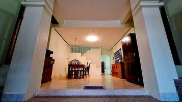 A hallway leading to a dining area with a staircase, a refrigerator, and a television.