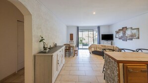 A spacious living area with a kitchen, dining table, and a sofa. - Villa "Apartment with Garden" with Mountain View, Private Terraces, and Air Conditioning (Aléria)