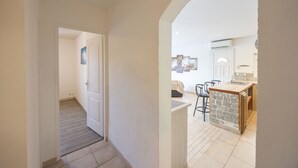 A hallway leading to a kitchen with a stone island and bar stools. - Villa "Apartment with Garden" with Mountain View, Private Terraces, and Air Conditioning (Aléria)