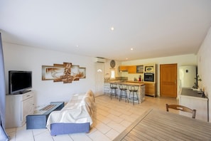 A modern living room with a sofa, a television, and a dining area with a table and chairs.