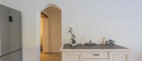 A kitchen with a refrigerator, cabinets, and a small table with decorative items.