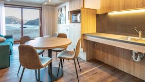 Una cocina moderna con armarios de madera, un comedor con una mesa redonda y sillas, y vistas a un paisaje nevado a través de un ventanal grande.