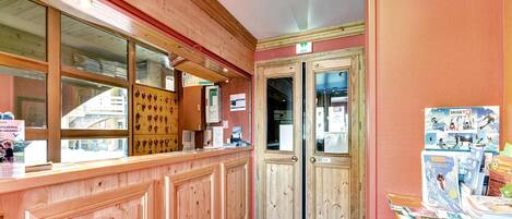 Un mostrador de recepción de madera con una ventana, una puerta y un tablón de anuncios con varios elementos.