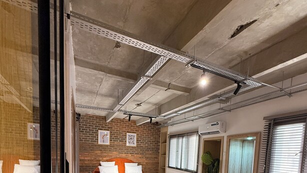 Una habitación de hotel moderna con una cama grande, una zona de estar con una silla amarilla y una pequeña mesa.